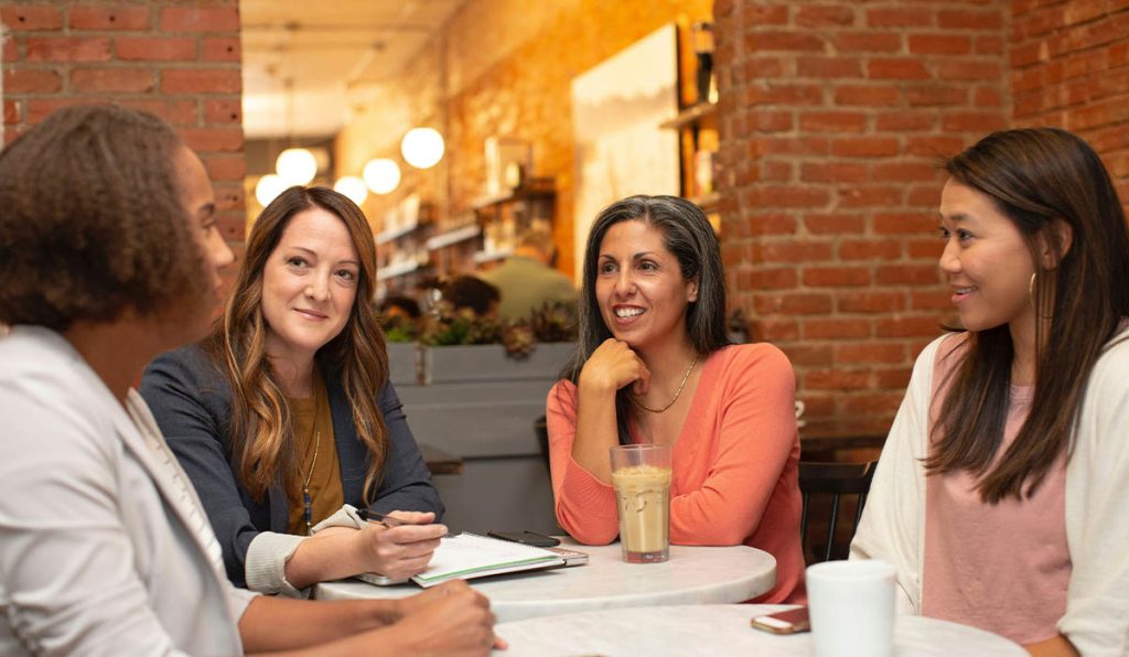 Group of professional women sitting around a table having a work meeting
